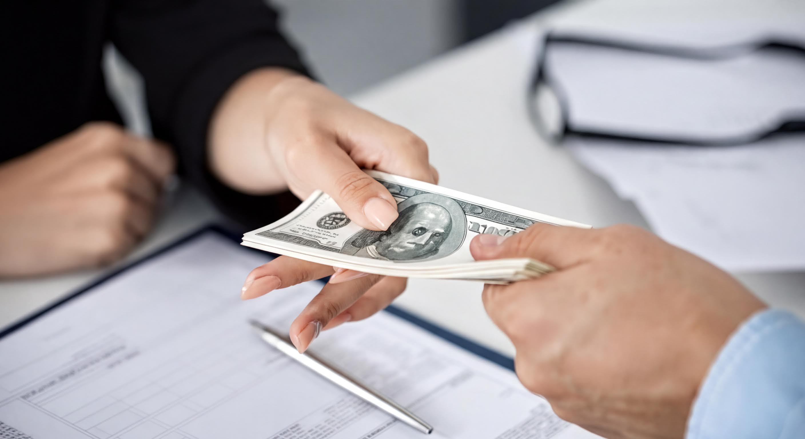 Business professional handing over money during financial planning session.